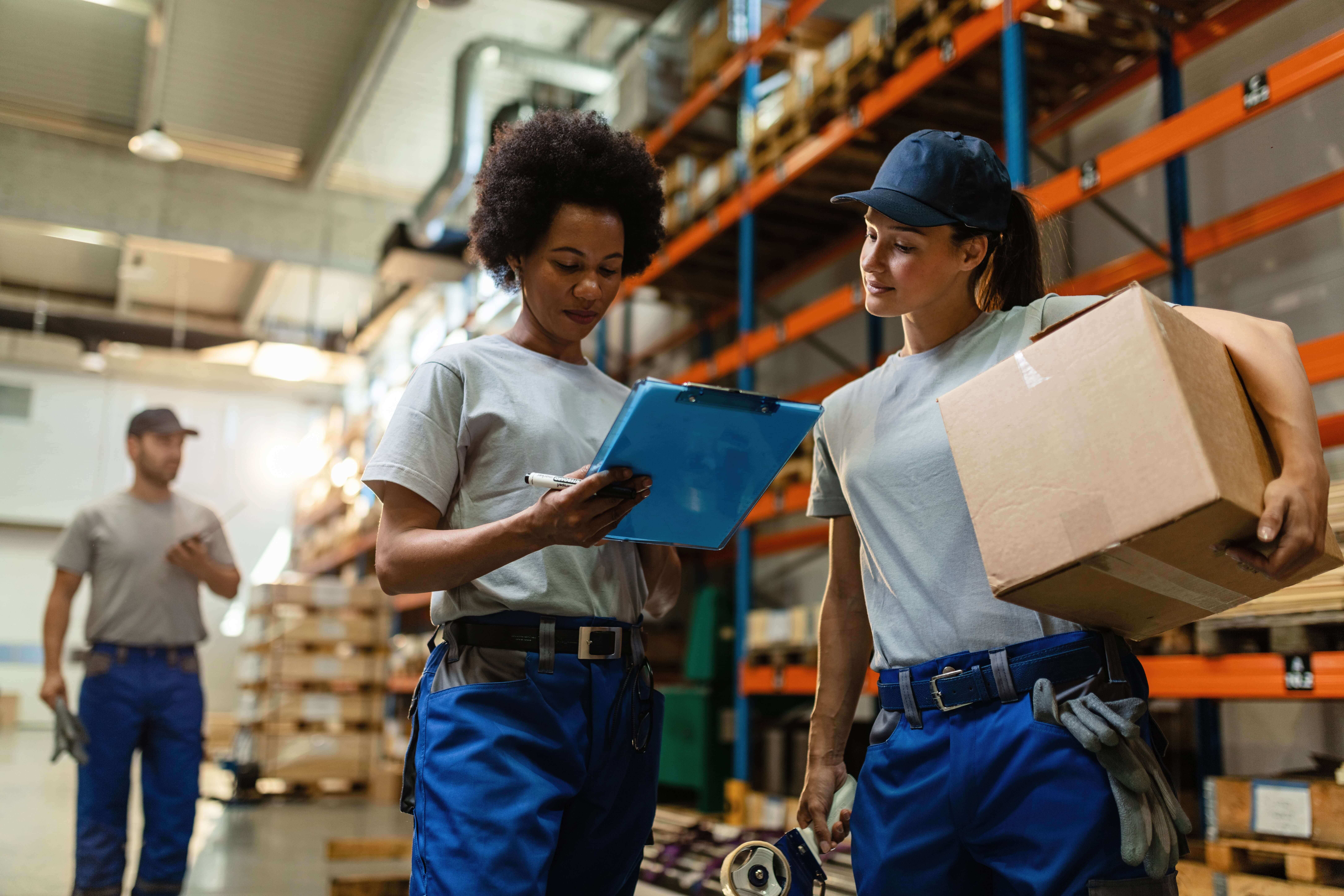 low-angle-view-two-female-workers-reading-delivery-schedule-list-while-working-distribution-warehouse (1) (1)